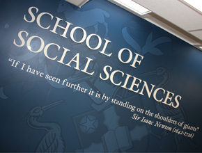 Photo of a blue wall with School of Social Sciences in white printed on